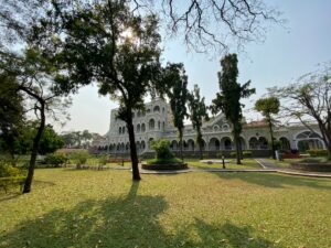 Historic Aga Khan Palace in Pune, India, with its grand white facade, arched windows, and sprawling green gardens, a prominent site of Indian freedom struggle and Mahatma Gandhi's imprisonment.