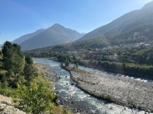 Serene view of the Beas River flowing through the scenic valleys of Manali, surrounded by lush greenery and snow-capped mountains.