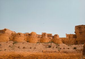 A panoramic view of Jaisalmer Fort, showcasing its golden sandstone architecture against a clear blue sky