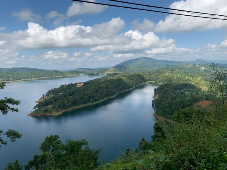 This image shows a scenic view of a calm lake surrounded by lush green hills